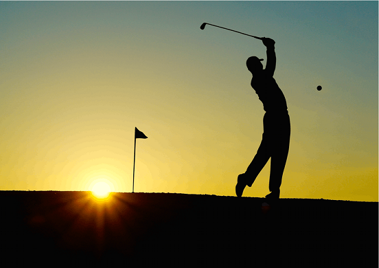 Golfer swinging club as sun sets